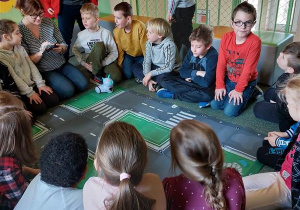 Nauczyciel tłumaczy dzieciom elementy programu robota, uczniowie słuchają zaciekawieni