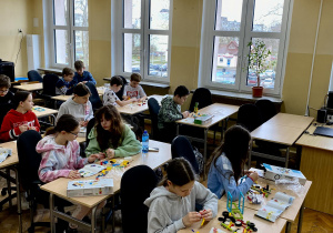 Uczniowie siedzą w sali i układają kolorowe klocki.