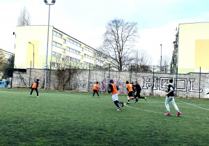 Chłopcy biegają po boisku szkolnym w trakcie meczu.