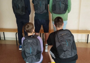 Grupa pięciu uczniów na korytarzu szkolnym.