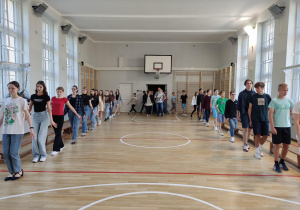 Uczniowie w trakcie próby tańca na sali gimnastycznej.