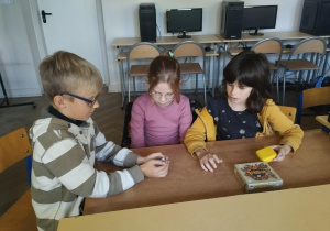 Trójka uczniów gra w grę planszową.