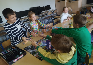 Grupa dzieci gra w Monopoly.