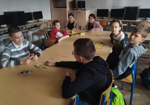 Grupa dzieci siedzi przy stolikach.
