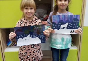 Dwie dziewczynki prezentują swoje prace plastyczne