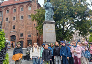 Grupa uczniów na tle pomnika Mikołaja Kopernika w Toruniu
