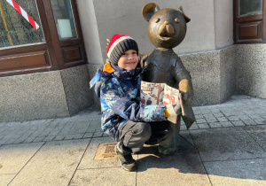 Chłopiec z książką przy pomniku Misia Uszatka.
