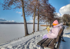 Dziecko z książką na ławce w parku.