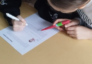 Dwie uczennice wspólnie rozwiązują zadanie na kartce.