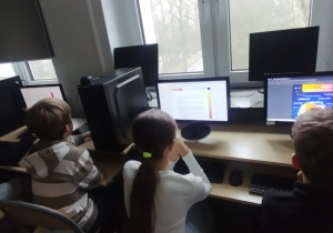 Uczniowie przed ekranami komputerów.