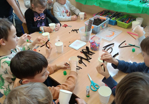 Grupa uczniów klas drugich wykonuje świąteczne zajączki.