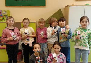 Grupa uczniów klas drugich prezentuje zajączki z rzeżuchą.