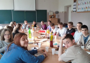 Duża grupa uczniów siedzi przy stole.