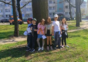 Grupa uczniów stoi pod drzewem.