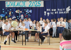 Grupa uczniów bierze udział w przedstawieniu na zakończenie roku szkolnego.
