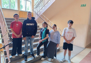 Grupa uczniów na schodach szkolnych.