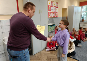 Pan Kamil wręcza nagrodę uczennicy z klasy 2