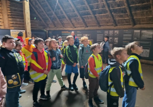 Grupa uczniów zwiedza chaty w Biskupinie