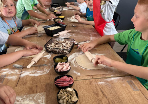 Grupka uczniów wykonuję pizzę