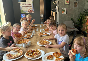 Grupka uczniów je własnoręcznie przyrządzoną pizzę