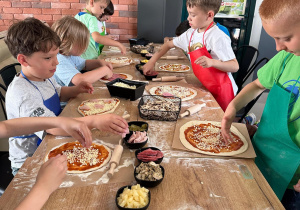 Grupka uczniów dekotuje pizzę