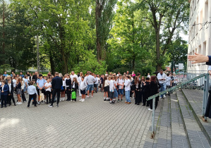 Duża grupa dzieci stojąca przed wejściem do szkoły.