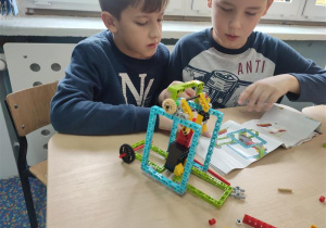 Dwóch chłopców odczytuje instrukcję i buduje z Lego