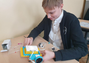 Uczeń składa robota z małych części.