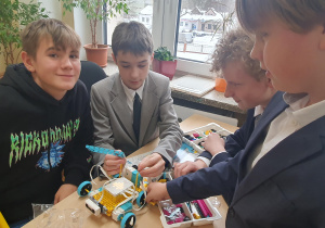 Czterech uczniów pracuje nad złożeniem robota.
